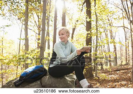 Stock Photograph - Female hiker using digital tablet in forest. Fotosearch