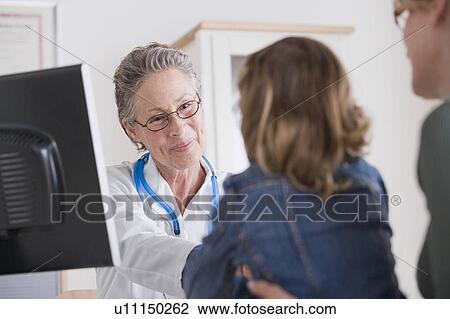 Stock Image - Female shaking hand with small girl (4-5) in her office. Fotosearch