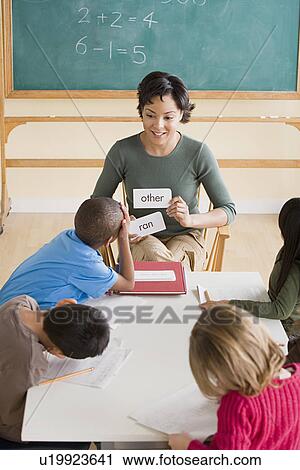 Stock Image - Female teacher with pupils (6-7) in classroom. Fotosearch