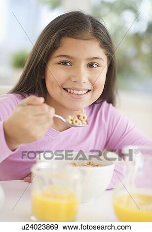 Stock Photo - Girl (10-11) having cereals for breakfast. Fotosearch