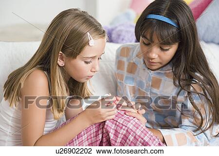 Girl (10-11) painting fingernails of her friend at slumber party View Large Photo Image Stock Image - Girl (10-11) painting fingernails of her friend at slumber party. Fotosearch