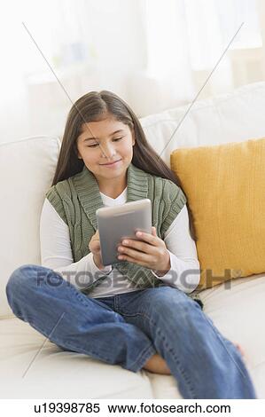 Girl (10-11) using digital tablet on sofa View Large Photo Image Stock Photography - Girl (10-11) using digital tablet on sofa. Fotosearch