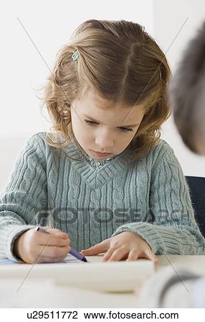 Stock Image - Girl (6-7) drawing in classroom. Fotosearch