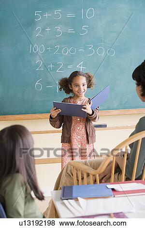 Stock Photo - Girl (6-7) having presentation in classroom. Fotosearch