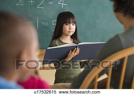Stock Photography - Girl (6-7) having presentation in classroom. Fotosearch