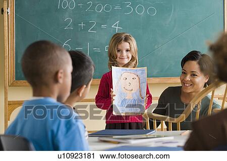 Girl (6-7) showing her drawing in classroom View Large Photo Image Stock Image - Girl (6-7) showing her drawing in classroom. Fotosearch