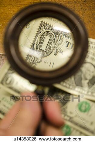 Hand holding magnifying glass over dollar bills, studio shot View Large Photo Image Stock Photograph - Hand holding magnifying glass over dollar bills, studio shot. Fotosearch