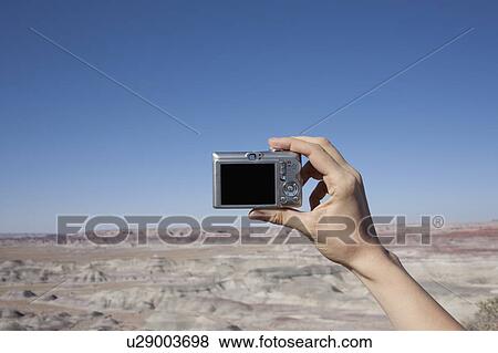 Hand of woman holding camera up against blue sky View Large Photo Image Stock Photo - Hand of woman holding camera up against blue sky. Fotosearch