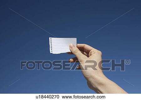 Hand of woman holding paper note against blue sky View Large Photo Image Stock Image - Hand of woman holding paper note against blue sky. Fotosearch