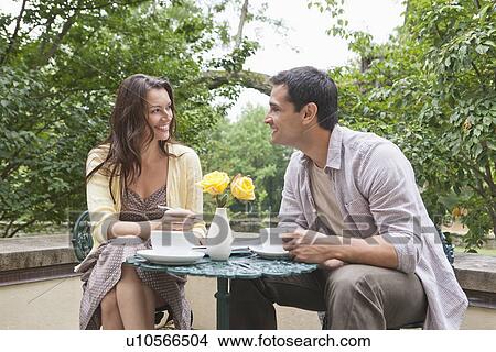 Picture - Happy couple sitting at table at outdoor cafe. Fotosearch