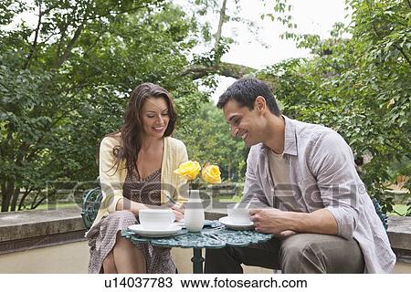 Happy couple sitting at table at outdoor cafe View Large Photo Image Stock Image - Happy couple sitting at table at outdoor cafe. Fotosearch