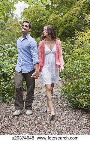 Happy couple walking through garden View Large Photo Image Stock Photo - Happy couple walking through garden. Fotosearch