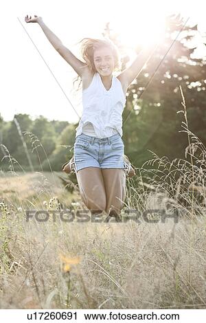 Stock Image - Happy teenage girl (16-17) jumping in bright sunshine. Fotosearch