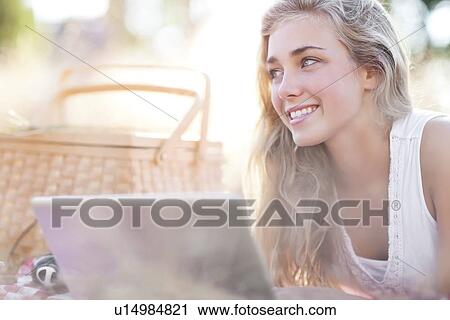 Stock Image - Happy teenage girl (16-17) using laptop outdoors. Fotosearch