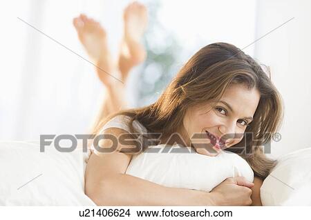 Picture - Happy woman lying on bed. Fotosearch