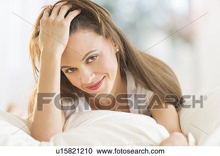 Stock Image - Happy woman lying on bed. Fotosearch