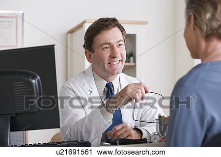 Male doctor talking to patient in his office View Large Photo Image Stock Image - Male doctor talking to patient in his office. Fotosearch