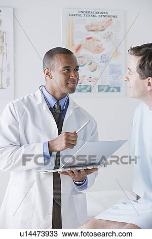 Stock Image - Male doctor talking to patient in hospital. Fotosearch