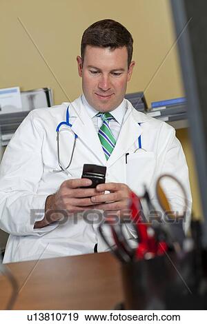 Stock Photo - Male doctor text messaging. Fotosearch