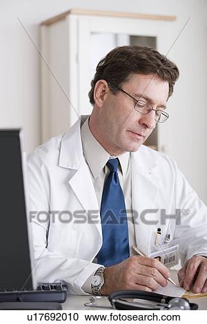 Stock Image - Male doctor working at desk. Fotosearch
