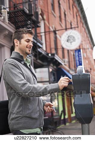 Stock Image - Man inserting coin to parking meter. Fotosearch