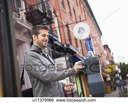 Stock Photograph - Man inserting coin to parking meter. Fotosearch