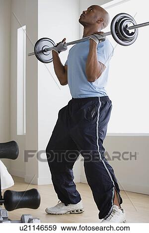Man lifting barbell in gym View Large Photo Image Stock Photo - Man lifting barbell in gym. Fotosearch