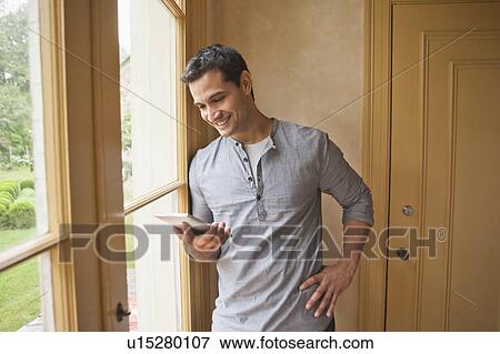 Stock Photo - Man reading e-book at home. Fotosearch