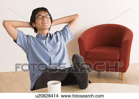 Picture - Man sitting with feet up on desk. Fotosearch