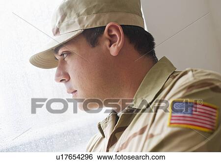 Stock Photograph - Man wearing military uniform looking through window. Fotosearch