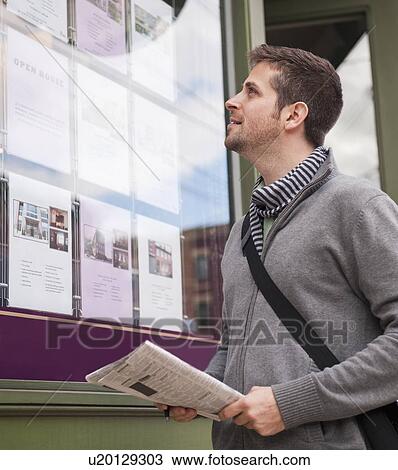 Man with newspaper looking at advert display View Large Photo Image Stock Image - Man with newspaper looking at advert display. Fotosearch