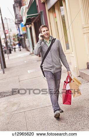 Man with shopping bags talking on mobile phone View Large Photo Image Stock Image - Man with shopping bags talking on mobile phone. Fotosearch