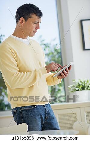 Stock Photograph - Mature man using digital tablet. Fotosearch