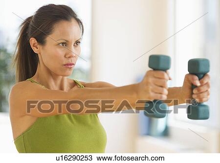Mid adult woman training with dumbbell View Large Photo Image Stock Image - Mid adult woman training with dumbbell. Fotosearch