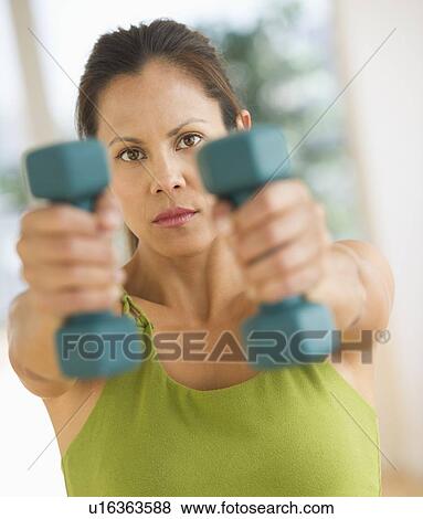 Mid adult woman training with dumbbell View Large Photo Image Stock Photo - Mid adult woman training with dumbbell. Fotosearch