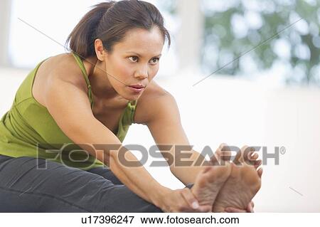 Stock Photo - Mid adult woman training with dumbbell. Fotosearch