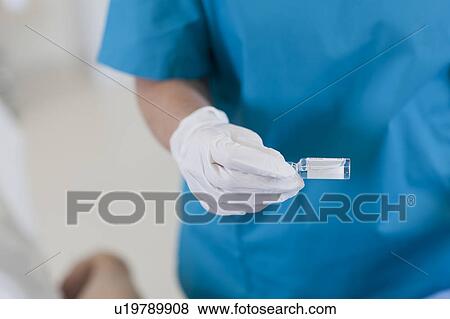 Midsection of surgeon holding vial View Large Photo Image Stock Photo - Midsection of surgeon holding vial. Fotosearch