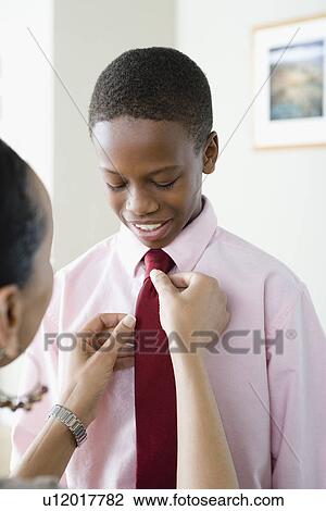 Stock Image - Mother adjusting Son's (12-13) tie. Fotosearch