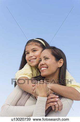 Stock Photo - Mother and daughter (10-11) embracing. Fotosearch