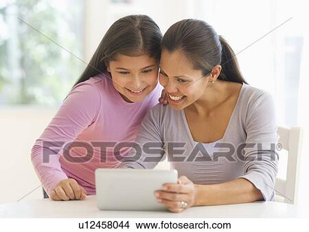 Picture - Mother and daughter (10-11) using digital tablet. Fotosearch