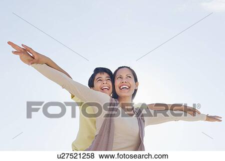 Stock Photo - Mother giving piggyback ride to her son (12-13). Fotosearch