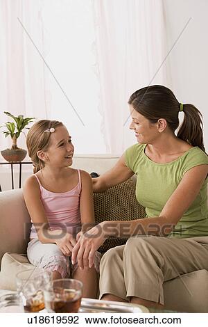 Stock Image - Mother talking to daughter (10-11) on sofa. Fotosearch