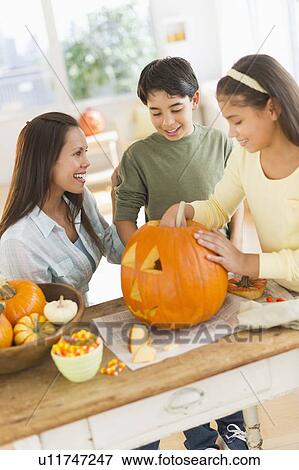 Mother with son (12-13) and daughter (10-11) doing Jack o lantern View Large Photo Image Stock Photo - Mother with son (12-13) and daughter (10-11) doing Jack o lantern. Fotosearch