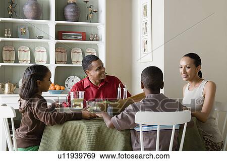 Parents and children (10-13) eating dinner together View Large Photo Image Stock Photo - Parents and children (10-13) eating dinner together. Fotosearch