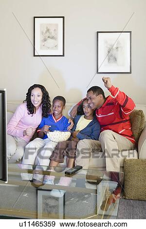 Parents and children (10-13) watching tv View Large Photo Image Stock Photo - Parents and children (10-13) watching tv. Fotosearch