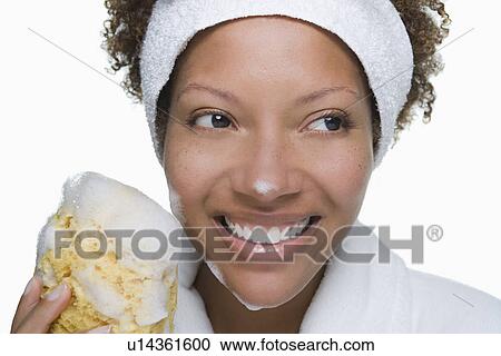 Stock Image - Portrait of attractive woman holding bath sponge. Fotosearch