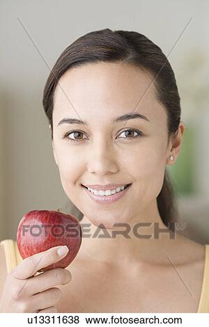 Stock Photo - Portrait of attractive woman holding apple. Fotosearch