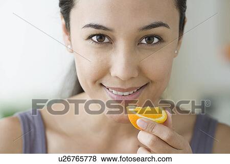 Portrait of attractive woman holding slice of orange View Large Photo Image Stock Photo - Portrait of attractive woman holding slice of orange. Fotosearch