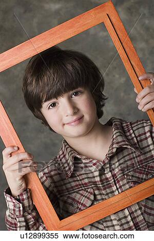 Portrait of boy (6-7) looking through frame, studio shot View Large Photo Image Stock Photography - Portrait of boy (6-7) looking through frame, studio shot. Fotosearch