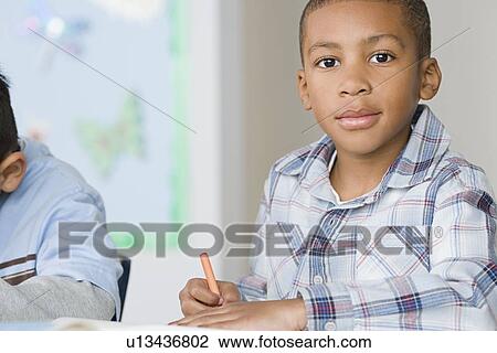 Stock Image - Portrait of boys (6-7) in classroom. Fotosearch